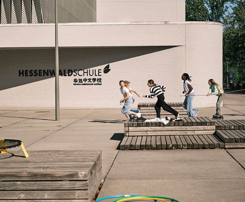 Kinder spielen auf dem Schulhof mit einem Seit und Inline-Skates
