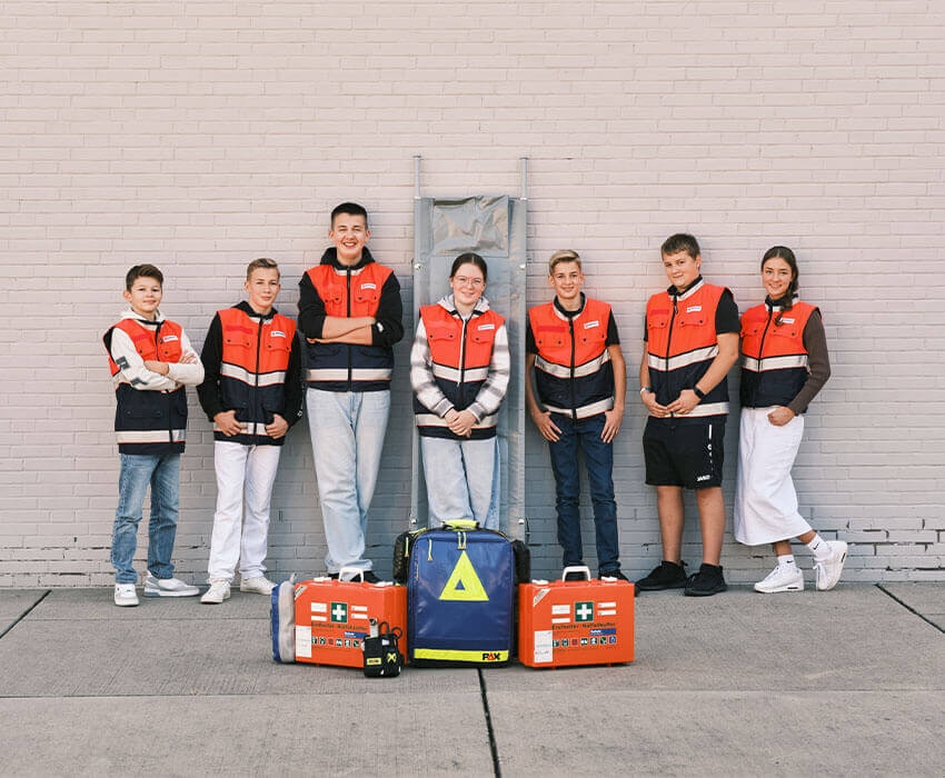 Eine Gruppe Schulsanitäter-AG Mitschüler steht vor einer Wand und posieren in die Kamera
